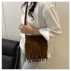 Detailed view of the brown suede fringe crossbody bag worn by a model in casual setting