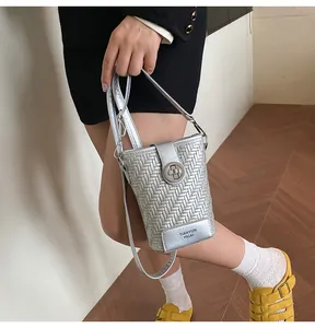 Detail van zilveren geweven crossbody telefoontasje met metalen slot en verstelbare riem