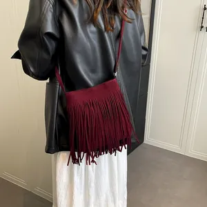 Vintage burgundy tassel crossbody bag in suede texture shown on female model shoulder