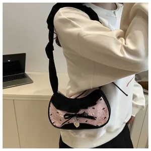 Dettaglio borsa rosa con volant neri, fiocco di nastro e ciondolo a cuore argento