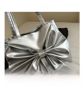 Close-up of the large bow detail on the metallic silver fashion tote bag with leather texture