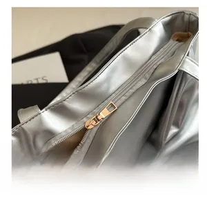 Close-up of smooth gold metal zipper and silver metallic fabric on tote bag