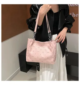 Détail du sac cabas en cuir rose avec bandoulière chaîne argentée et motifs