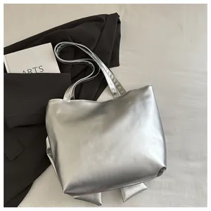 Detail of a shiny silver metallic tote bag featuring a reflective mirror-like finish texture
