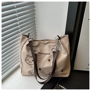 Dettaglio della borsa tote beige con ricamo a gatto e tracolla in pelle e catena