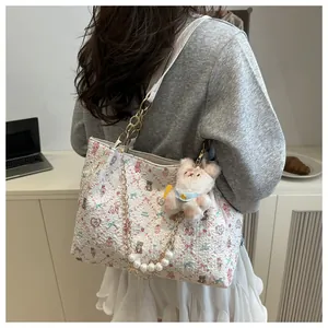Detail van de bloemen tote bag met gouden ketting, parelhanger en pluche beer decoratie