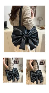Close-up of black tote bag featuring a large glossy PU leather bow and long shoulder straps