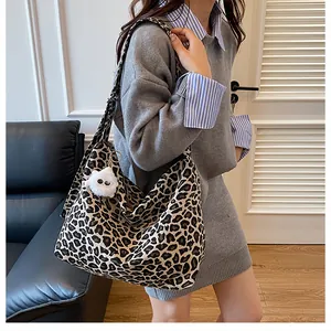 Dettaglio della borsa tote in tela leopardata con un simpatico ciondolo mostro di peluche bianco