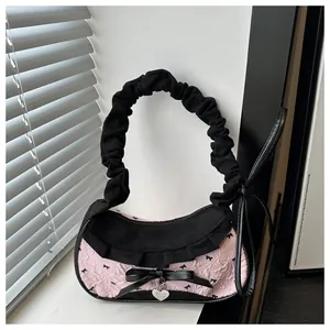 Dettaglio della borsa rosa con ricamo a fiocchi neri e ciondolo a cuore elegante