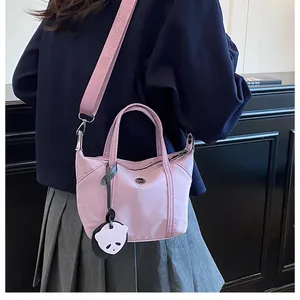 Détail du sac en nylon violet porté en bandoulière avec sangle large et pendentif panda