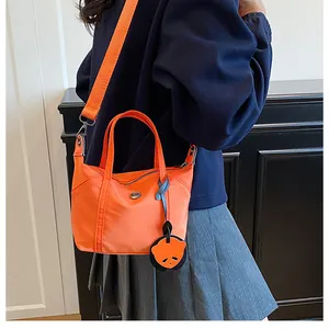 Détail du sac bandoulière en nylon orange avec breloque panda et logo métallique