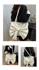 Detail view of cream shoulder tote bag with oversized decorative bow and double straps