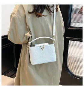 Détail du sac bandoulière tressé blanc avec logo V doré et sangle pour porté croisé