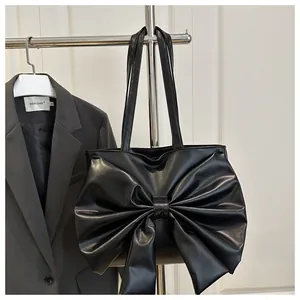 Detail of black PU leather tote bag featuring a large decorative bow and twin straps