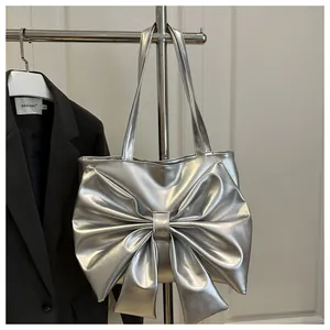 Detail of silver metallic tote bag with large bow and glossy finish on a stainless hanger