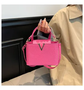 Détail du sac à main en cuir tressé rose avec fermoir en V doré tenu par mannequin