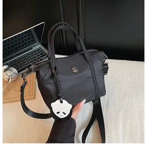 Détail du sac en nylon noir avec logo rond et pendentif panda mignon et amovible