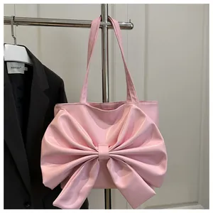 Close-up of pink tote bag with a large decorative bow and matte PU leather texture
