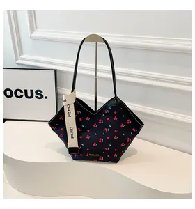 Détail du sac cabas noir à imprimé cerise avec bords festonnés et sangle décorative