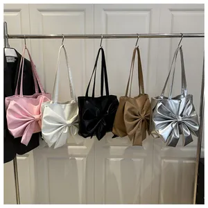 Multiple colors of stylish tote bags with large bow accents displayed on a rack