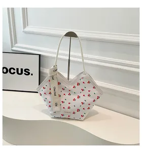 Détail du cabas blanc à motif cerises avec ruban décoratif sur la bandoulière