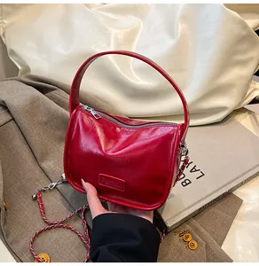 Close-up of red glossy patent leather handbag with a silver chain and fashion plate