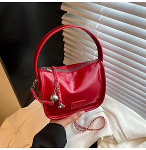 Detail of red glossy faux leather handbag with metal chain and silver ball charm
