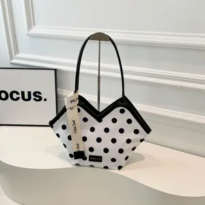 Sac fourre-tout à pois avec lanières en cuir et ruban décoratif sur présentoir épuré