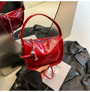 Close-up of shiny red patent leather handbag with silver chain and Fashion label