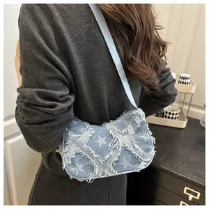 Blue denim star patchwork crossbody bag with frayed edges worn by a model
