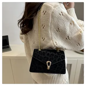 Fashionable black leopard pattern crossbody bag with gold chain strap on a model