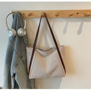 Détail du cabas en toile avec des lanières en cuir marron et des coutures décoratives en V