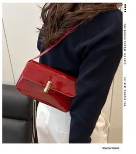Close-up of a stylish red patent leather shoulder bag with a sleek gold metal buckle