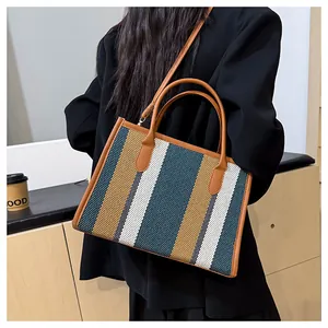 Detailed side view of large striped tote bag with woven texture and leather straps