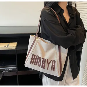 Détail d'un sac cabas en toile crème avec bordure en cuir marron et lettrage Hoorya