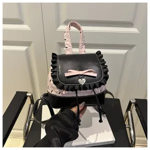 Detail der rosa Schleife und des Herzanhängers an einem schwarz-rosa Rucksack