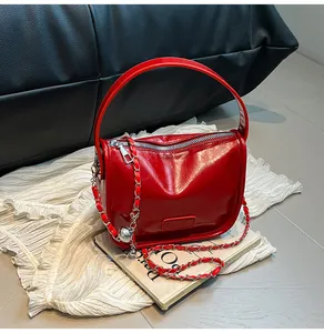 Detail of red patent leather shoulder bag with silver chain and Fashion metal plaque