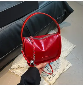 Detailed shot of glossy red faux leather handbag with silver chain and metal ball charm