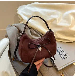 Close-up of suede tote bag texture with elegant bow and golden heart charm detail