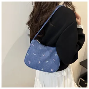 Detail of denim blue hobo bag with colorful butterfly embroidery and metal zipper