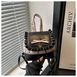 Detail der rosa Schleife und Herzanhänger am rüschigen schwarz-rosa Rucksack