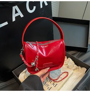 Close-up of red shiny patent leather handbag with silver metallic ball chain strap