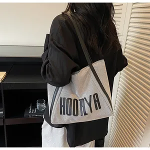 Détail du sac cabas en toile grise avec broderie HOORYA et bandoulières en cuir noir