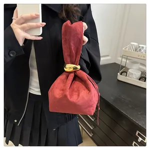 Detail of dark red suede bucket bag featuring a decorative gold-tone metal ring handle