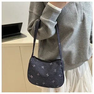 Detail of dark blue denim underarm bag with colorful bows shown in a casual lifestyle scene