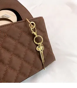 Close-up of dark brown quilted crossbody bag with soft matte texture and gold key charm