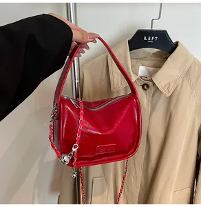 Close-up of red glossy patent leather handbag featuring silver chain and Fashion embossing
