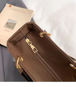 Close-up of golden zipper hardware and quilted stitching on brown faux leather bag