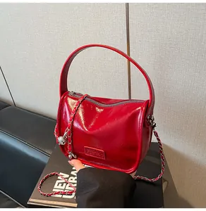 Detail of red glossy faux leather crossbody bag with chain strap and Fashion label