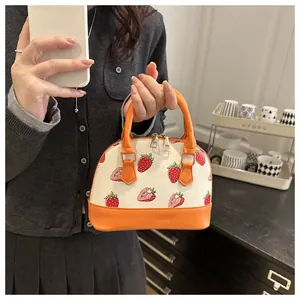 Vue détaillée d'un mini sac coquille crème avec imprimés fraises et anses en cuir orange